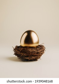 Golden Egg In The Nest Isolated On Champagne Color Background. Minimal Easter Layout With Copy Space. Creative Investments, Savings, Funding And Pensions Concept.