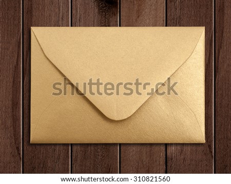 Golden envelope over wooden table.