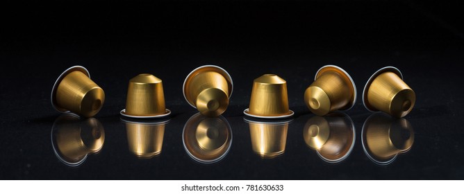 Golden espresso coffee capsules isolated on black background, Closeup view with details, banner