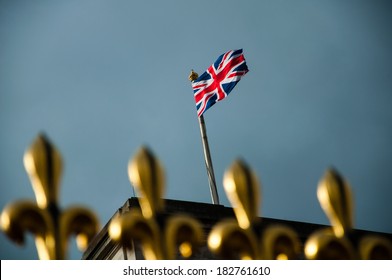 Golden Fence Of Buckingham Palace With British Flag