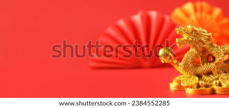 Golden figurine of Chinese dragon on red background with space for text