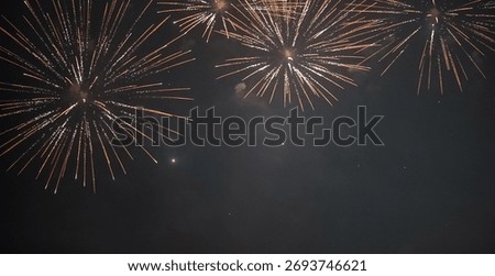 Golden fireworks exploding in the night sky with glowing trails and a festive glow.