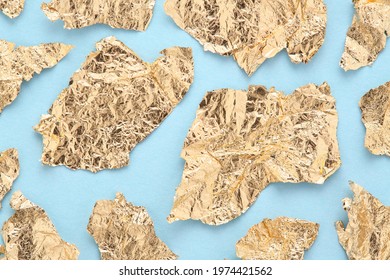 Golden foil pieces on blue abstract background, torn gold paper pattern. - Shutterstock ID 1974421562