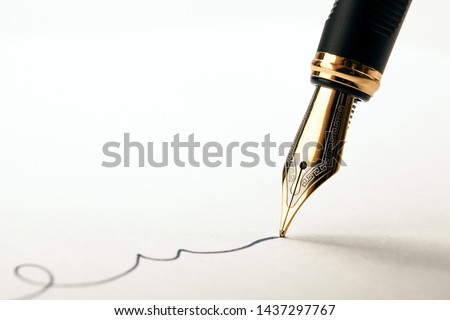golden fountain pen leaves a signature on a white paper closeup