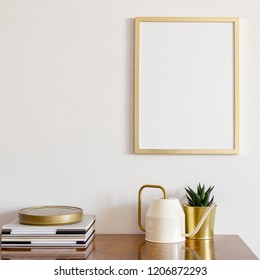 Golden frame over cabinet with golden flower pot and watering can on white wall. Minimal design. Mock up