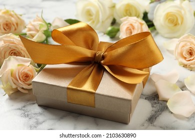 Golden gift box and beautiful roses on white marble table - Powered by Shutterstock