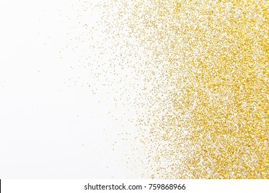 Golden glitter sand texture on white, abstract background. Yellow dusty shimmer decoration, shiny and sparkling frame, top view, copy space. Holidays and glamour concept.