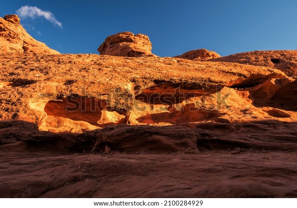 Golden glow of the morning light on Navajo\
sandstone rock formations.  The red color is the result of deposits\
of iron oxide in the\
soil.