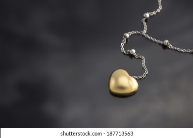 Golden heart with necklace chain on black  background.