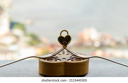 Golden Heart Shaped Love Padlock Over Two Intertwined Gold Forks On Gold Heart-shaped Box. Valentine's Day Concept, Copy Space, Selective Focus.