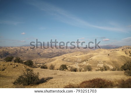 Golden hills with trees and roads in clear day