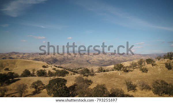 Golden hills with\
trees and roads in clear\
day