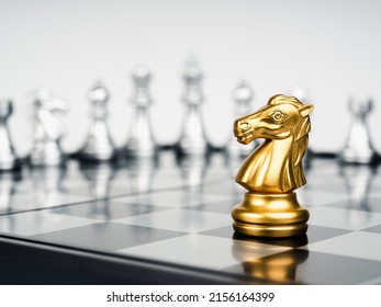 The golden horse, knight chess piece stand alone in front of silver chess pieces on chessboard on white background. Leadership, fighter, surviver, competition, and business strategy concept. - Shutterstock ID 2156164399