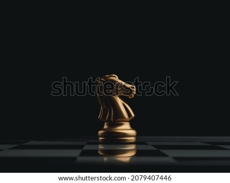 The golden horse, knight chess piece standing alone on chessboard on dark background. Leadership, influencer, strong, commander, competition, and business strategy concept.
