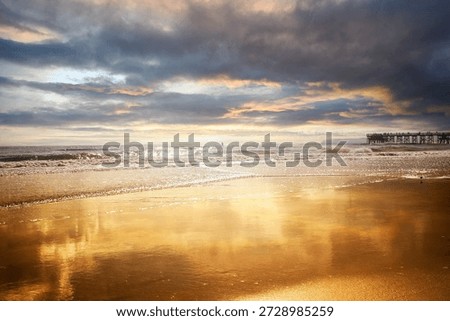 Golden hour beach reflection with dramatic clouds and distant pier at sunset