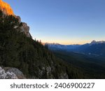 Golden hour hitting the tips of Canadian mountain range with forest valley below