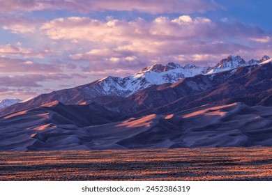 Golden hour light warms up the peaks of the Sangre de Cristo Mountains and the tops of the sand dunes in Great Sand Dune National Park, Colorado