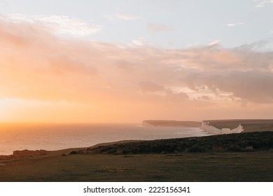 Golden hour pastel coloured sky over the Seven Sisters chalk cliffs, one of the longest stretches of undeveloped coastline on the south coast, East Sussex, UK.