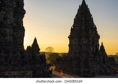 Golden Hour At Prambanan Temple, Yogyakarta. You Can See A Woman In An Orange Dress Taking A Selfie.