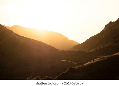 Golden hour soft light sun rays backlight rolling hills green grass farm meadow pasture mountain landscape at Kaihoka Lakes Tasman South Island New Zealand