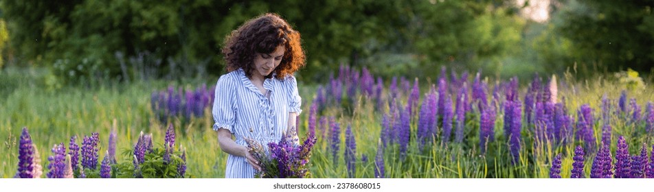 Golden hour, sunset, summer. Beautiful happy young woman on meadow arranging table for outdoor event, gathering wildflowers. Wedding or romantic date decoration in the field with purple lupins - Powered by Shutterstock