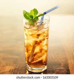 golden iced tea with blue straw and mint