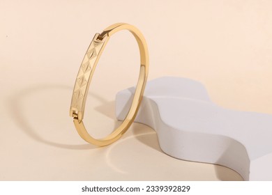 Golden jewelry Bracelet on blue and white podium  