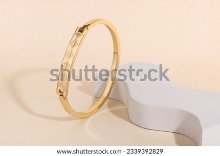 Golden jewelry Bracelet on blue and white podium  