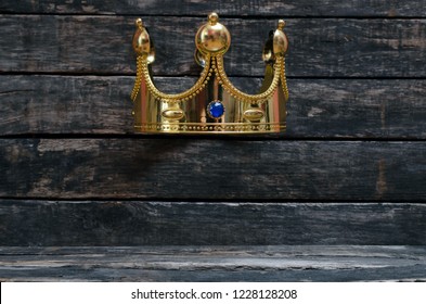 Golden King Crown On Wooden Wall Background With Copy Space For Unique Object Below It. Premium Product Presentation Concept.