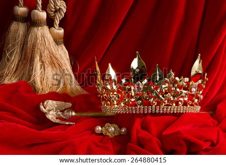 Golden king's crown and scepter on red velvet