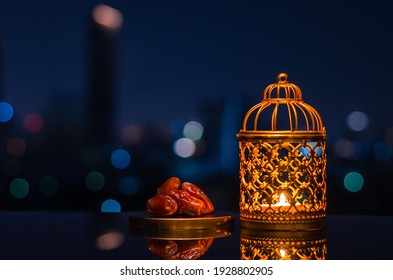 Golden Lantern And Dates Fruit With Night Sky And City Bokeh Light Background For The Muslim Feast Of The Holy Month Of Ramadan Kareem.