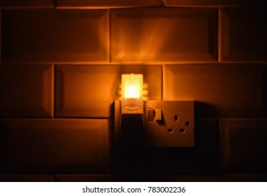 The Golden Light From The Bulb And Shadow That Plugs In Middle Of The Wall. Concept Night Light In The Dark.