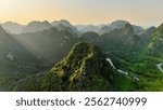 Golden Light on Limestone Peak: Aerial View of Dramatic Mountain Valley with Meandering River at Sunset in Asia