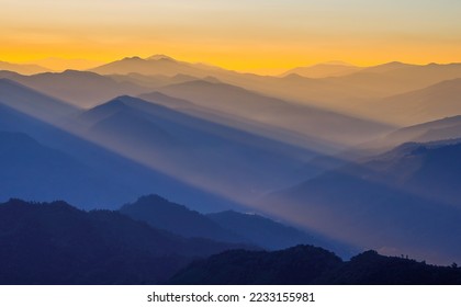 Golden light rays shining down to mountains. Sun rays over valley. Sun rays over hill. Beam of light from clouds on the mountains. oblique rays of sunlight through the mountains. Doi Pui Co, Thailand. - Powered by Shutterstock