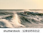 Golden light shining on large waves with a surfer in the background. Montauk State Park, New York. 