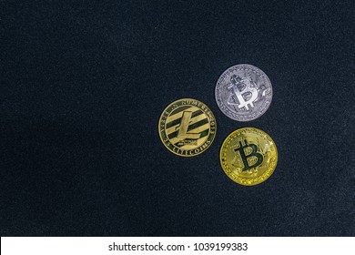 golden litecoin and two bitcoin lie on dark abstract background

