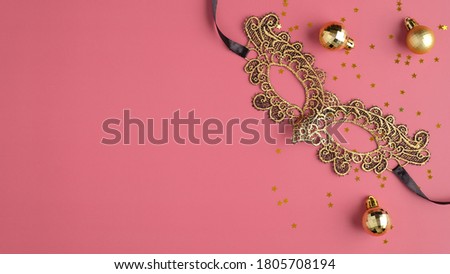 Golden masquerade mask and Christmas balls decorations on pastel pink background. Flat lay, top view. Christmas party banner mockup.