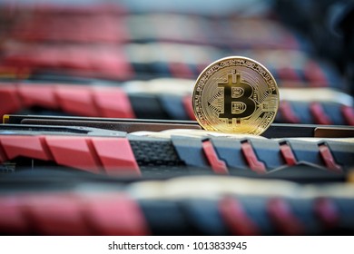 Golden metal coin as symbolic version of Bitcoin cryptocurrency on a background of mining electronic parts . Cryptocurrency mining and trading concept.  - Shutterstock ID 1013833945