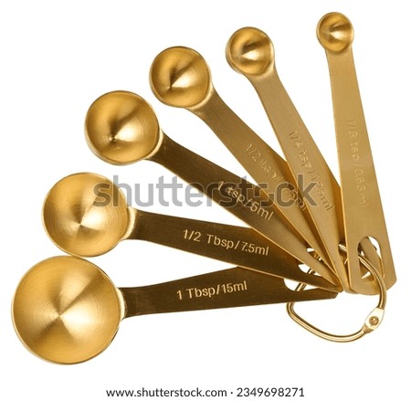 Golden metal measuring spoons for bulk and liquid products on a white isolated background, top view