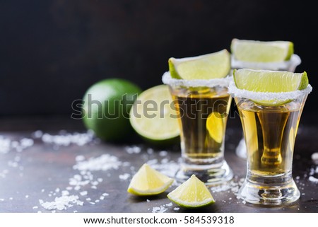 Golden mexican tequila shot with green lime and salt