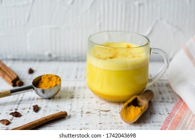 Golden milk with curcuma powder, Turmeric latte with spices on a white background, Hot healthy drink. Healthy ayurvedic drink. Detox beverage with spices for vegans.