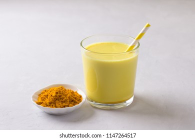 Golden milk with turmeric in a glass on a gray stone background. healthy natural energy drink. selective focus