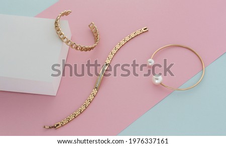Golden modern bracelets on pastel colors paper background 