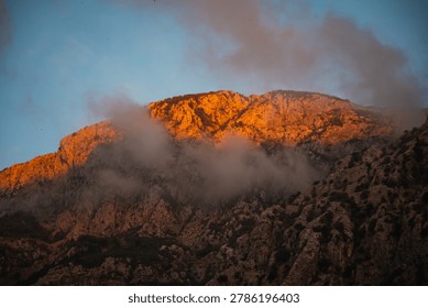 Golden Mountain with Dramatic Sunset Clouds. Warm Sunset Light Over Rugged Cliffs.