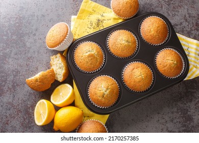 Golden muffins with poppyseeds and lemon zest close-up in a metal muffin pan on the table. horizontal top view from above