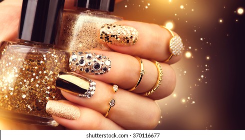 Golden Nail art manicure. Holiday style bright Manicure with gems and sparkles. Bottle of  Nail Polish. Fashion rings with diamonds, Trendy Accessories. Beauty hands. Stylish Nails, Nailpolish