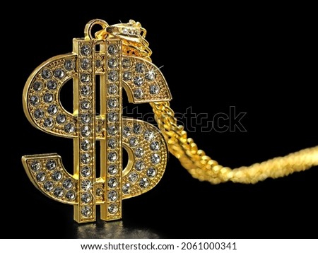 golden necklace dollar symbol with sparkling diamonds isolated on black background, close up