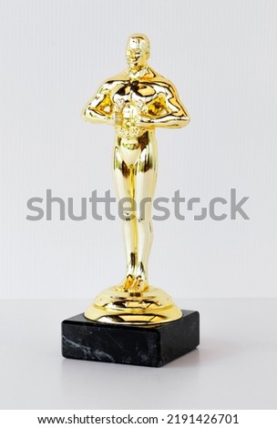 golden oscar statuette, on white table, concept of success and victory.