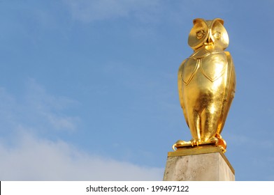 Golden owl sculpture against blue sky 