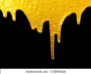 Golden paint dripping liquid paint, isolated on black background. Flowing abstract Gold metallic paint drops close-up. Leaking.gold paint dripping or flowing on black background 